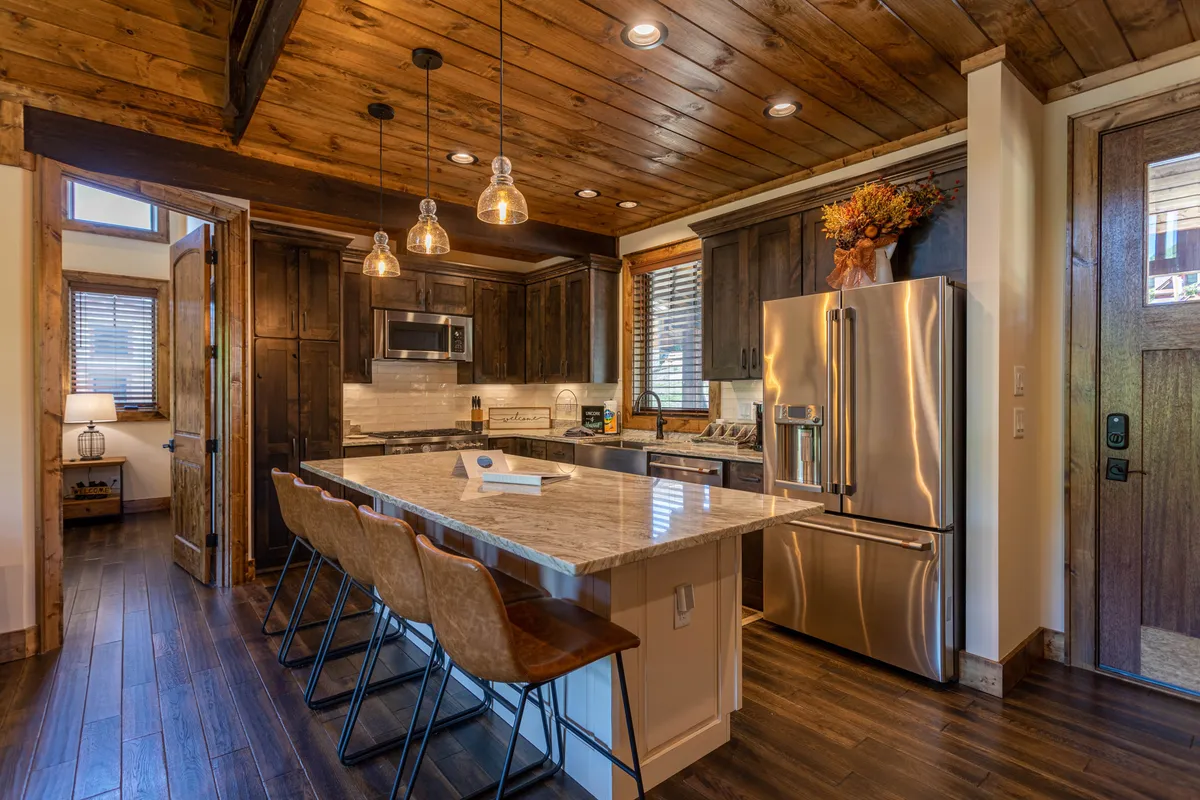 The kitchen is the star here, with granite countertops, stainless steel appliances, a spacious island, pendant lighting, and ample wooden cabinetry. The setup is clearly designed for cooking, entertaining, and family meals.