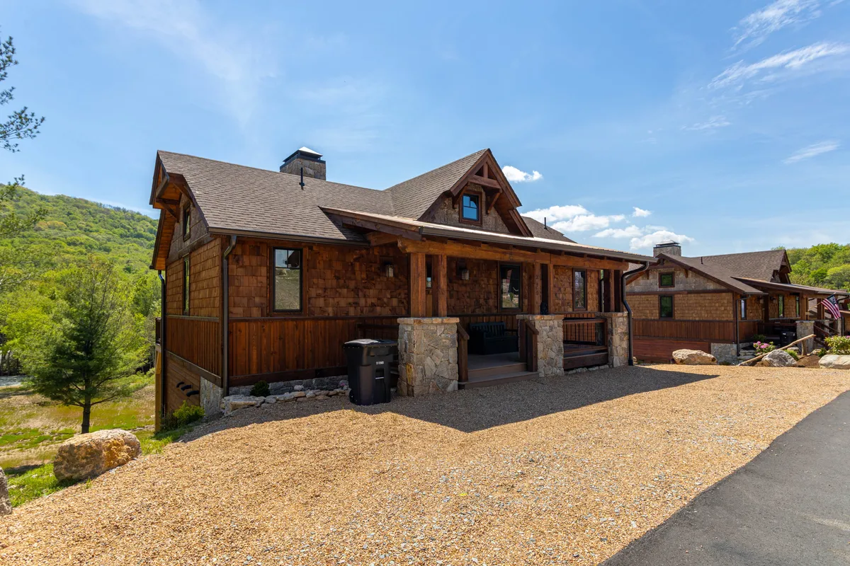 A welcoming wooden exterior with stone accents and a front porch set against a peaceful backdrop, ideal for relaxing outdoors. The scene evokes a sense of arrival and provides a glimpse of the retreat's inviting atmosphere.